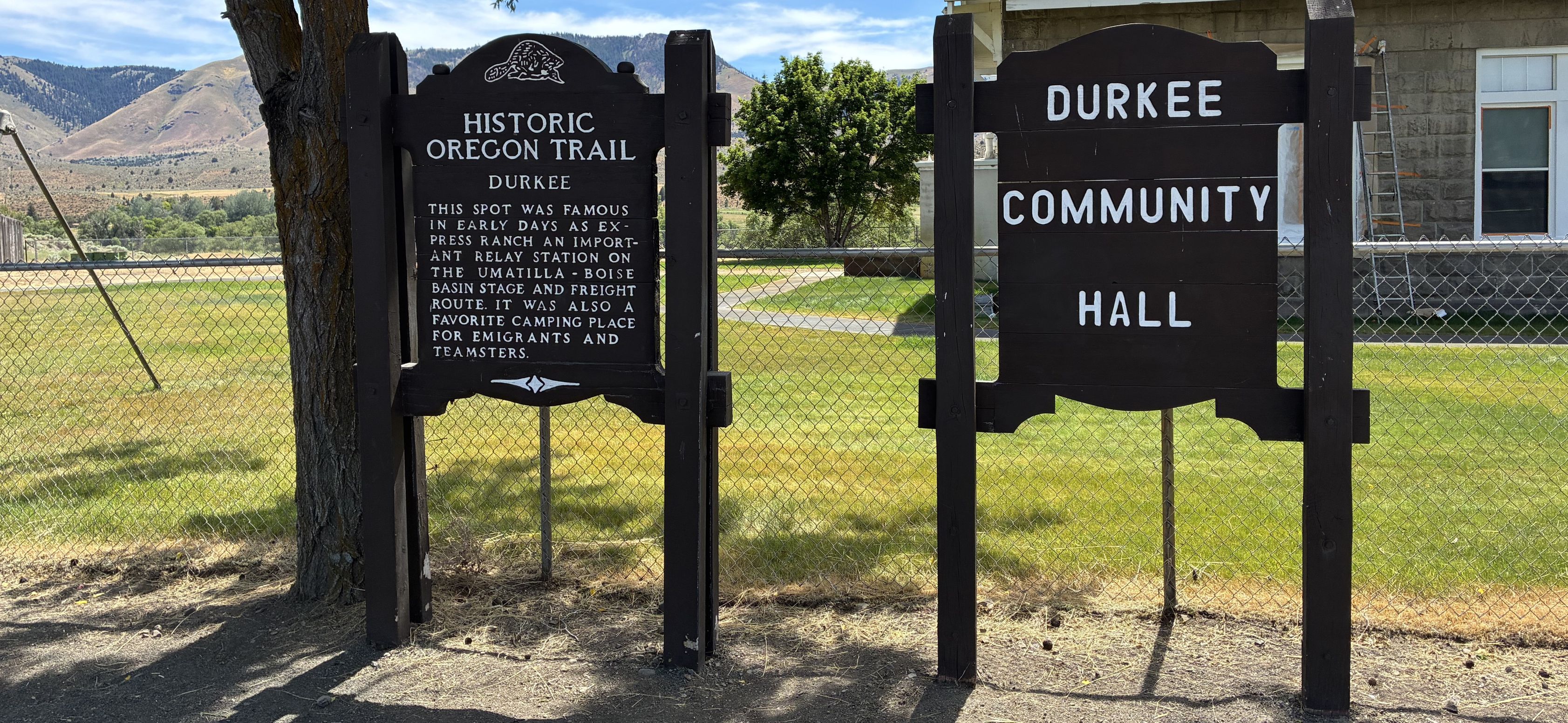 Two wooden signs in front of historic school.