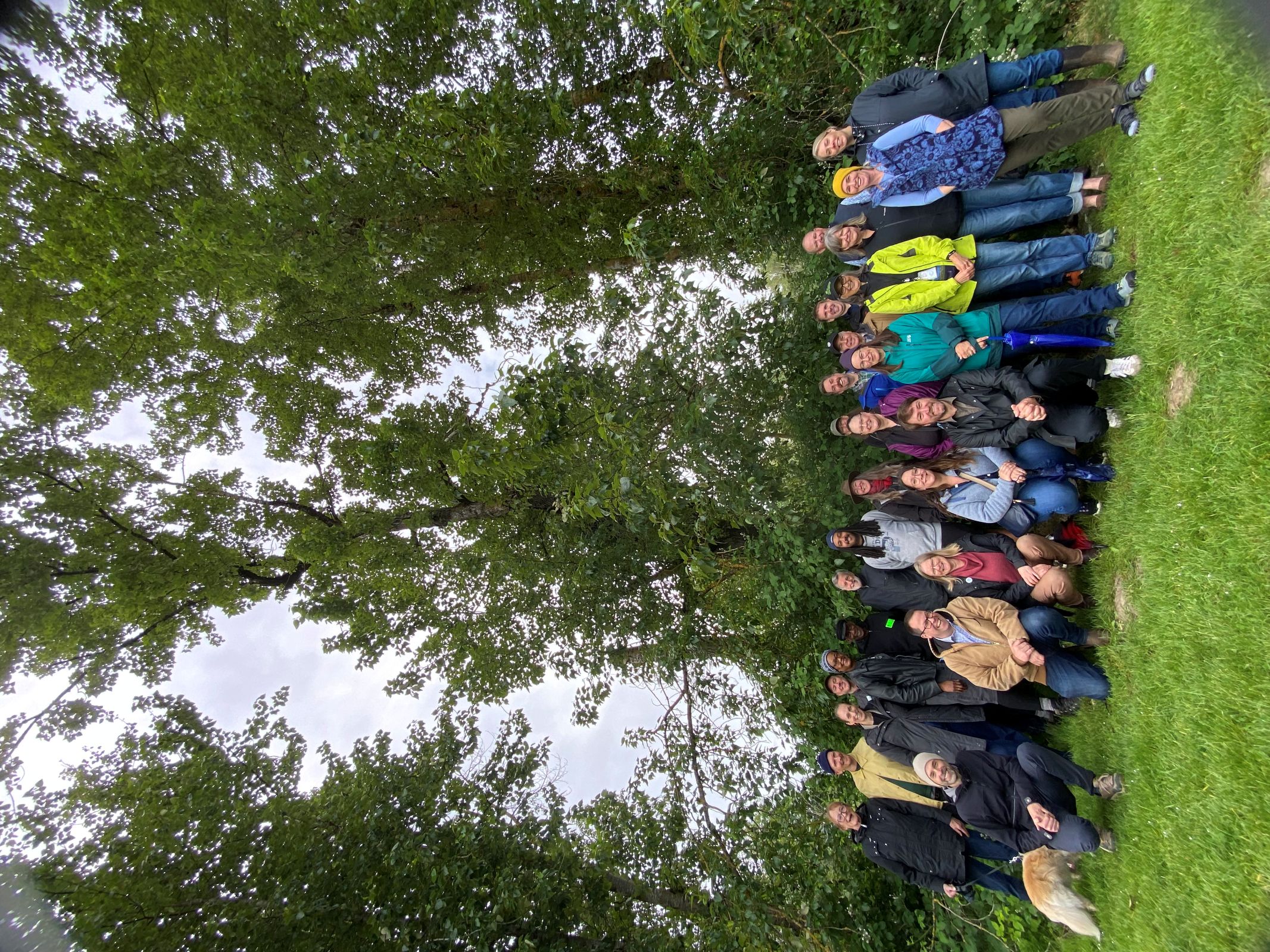 Photo of large group of people in front of cottonwood trees, posing with new plaque. 